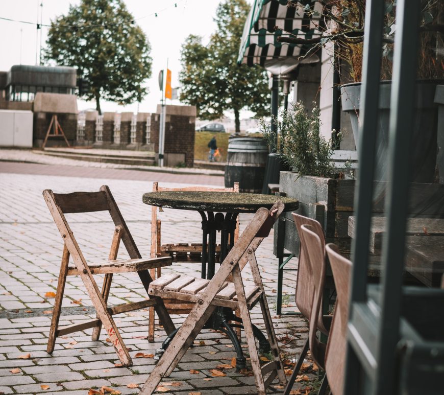 Leeg Terras in Rotterdam in de buurt van de Straatweg. Niet gebruikte houten meubilair, gecombineerd met de luifel in Rotterdams groen-wit geeft een rust of leegte aan.