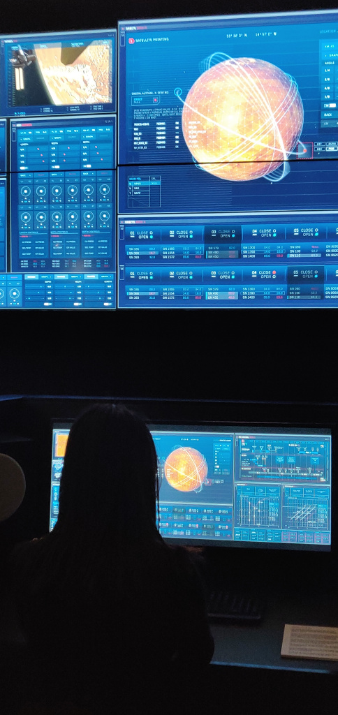 Interfaces voor fictieve mission control, op het scherm is een mars achtige planeet te zien met meerdere banen voorwerpen in banen om de planeet.