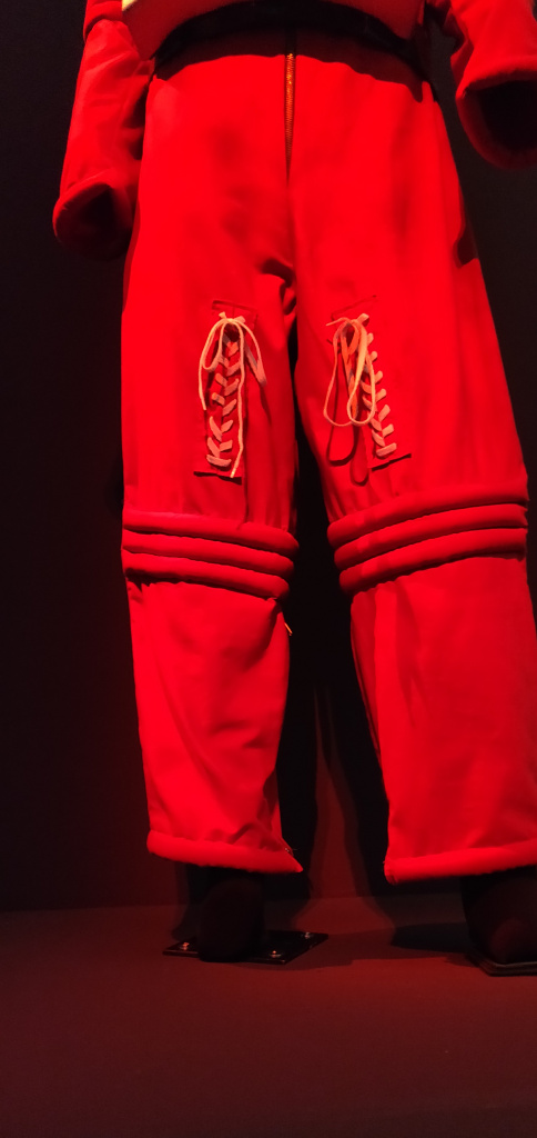 Broekgedeelte van oranje ruimtepak, jaren 60 stijl met opvallende oranje veters op de dijbenen