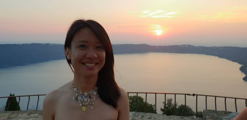 Vi voor het Albanomeer (Lago Albano), in Italië op de dag van de bruiloft van Remco en Ebony. Ze draagt een prachtige kettings met veel boemen details. Op de achetergrond gaat de zon onder en is het meer nog goed te zien.