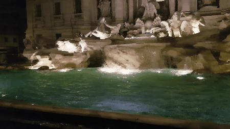 Beroemde Trevifontein in Rome, midden in de nacht. De stenen beelden op de fonteint worden verlicht vanuit het water.