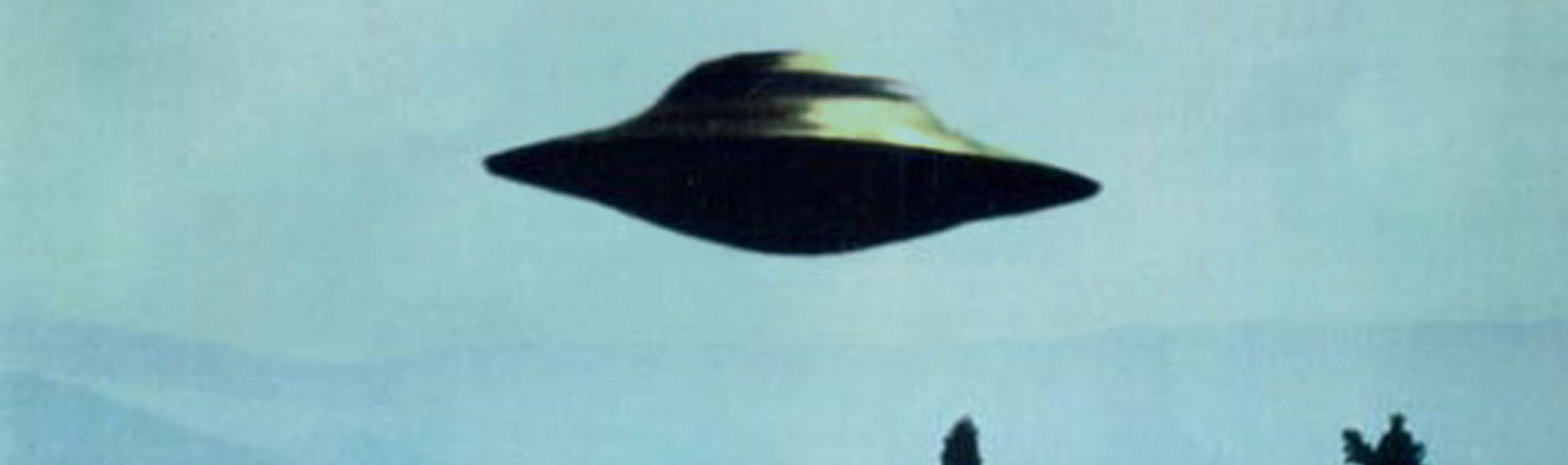 Banner versie van een iconische I Want To Believe poster, gepopulariseerd in de tv-serie X-files. Een bekende UFO foto, een schijf zweven boven bomen en heuvels, met de tekst I want to believe aan de onderkant.