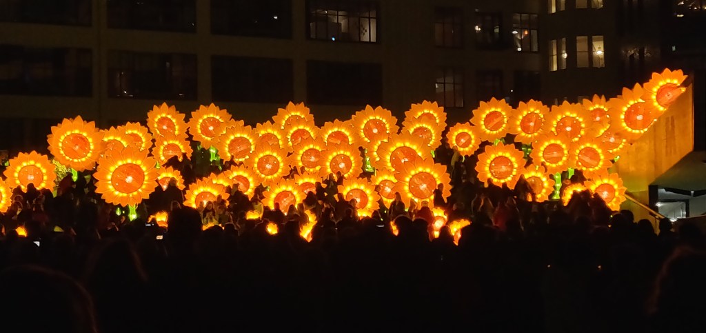 Zonnebloemen voor Van Gogh. Tig grote gele en oranje lichtgevende zonnebloemen over een hene brede trap verspreid.