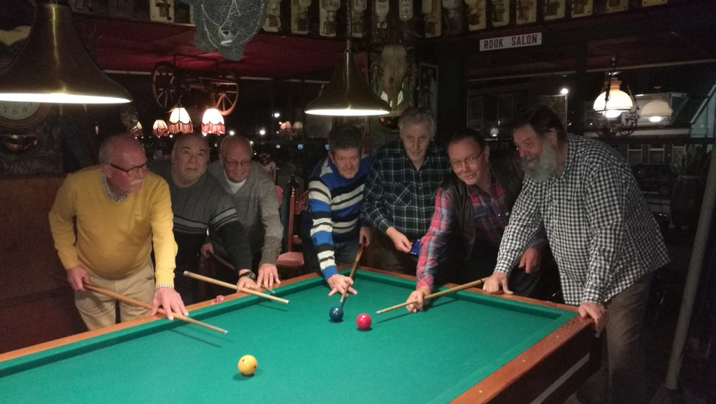Pa met zijn biljartcollega's allen keu in de aanslag, rondom een biljarttafel.
