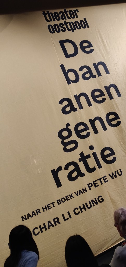 De banner aan het begin van de voorstelling van De Bananengeneratie. Er staat op Theater Oostpool, De Bananengeneratie, naar het boek van Pete Wu, Regie Char Li Chung. De titel De Bananengeneratie heeft een specifiek enjambement.